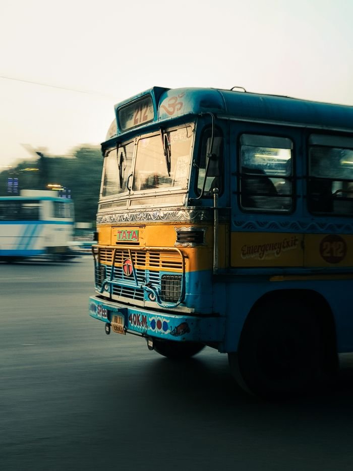 A vibrant vintage bus captured in motion on an urban street during the day.
